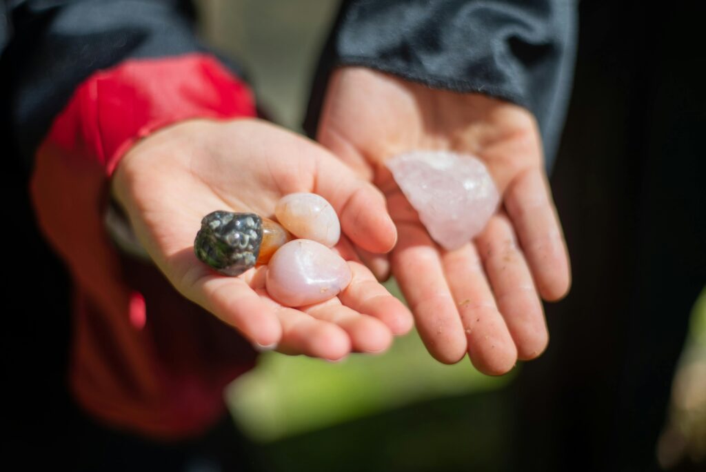 Two hands displaying vibrant gemstones outdoors in natural light.